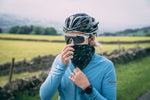 A female cyclist with a black and green VOOM bandana worn over the lower part of her face like a snood