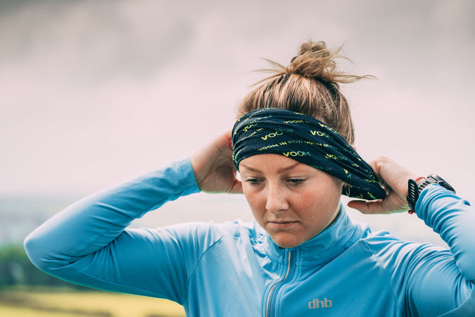 A female runner adjusts the VOOM bandana worn as a head band to keep her hair in place